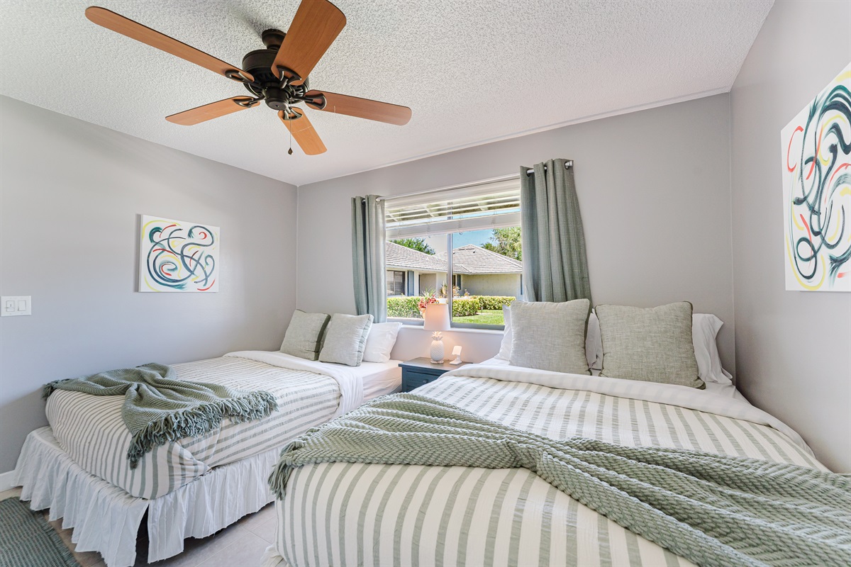 Bright guest bedroom with two queen beds, Smart TV with cable, and ample closet and dresser storage
