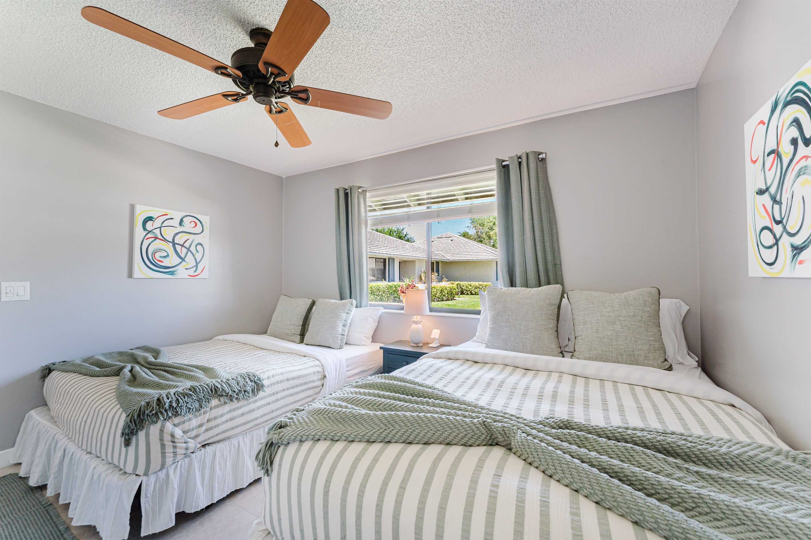 Bright guest bedroom with two queen beds, Smart TV with cable, and ample closet and dresser storage

