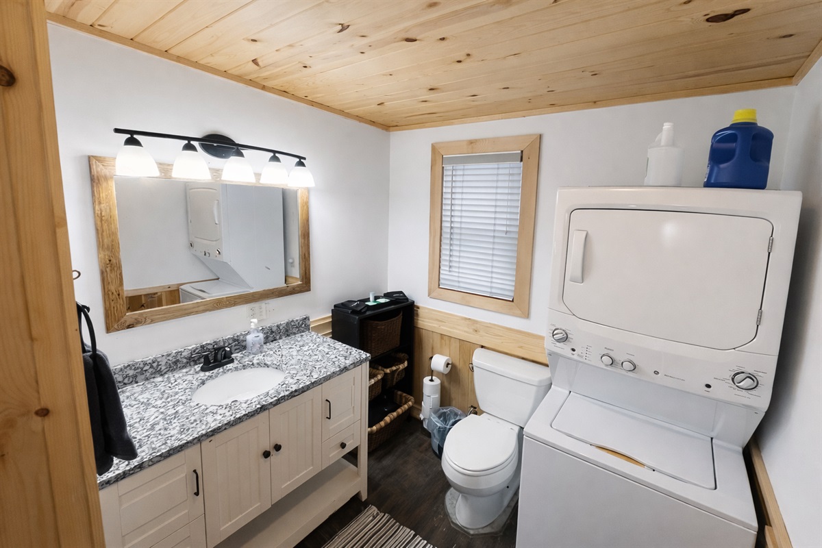 A beautifully updated bathroom with a stone countertop and warm, modern lighting. Conveniently equipped with an in-room washer and dryer, it’s both stylish and practical for longer stays and added comfort.