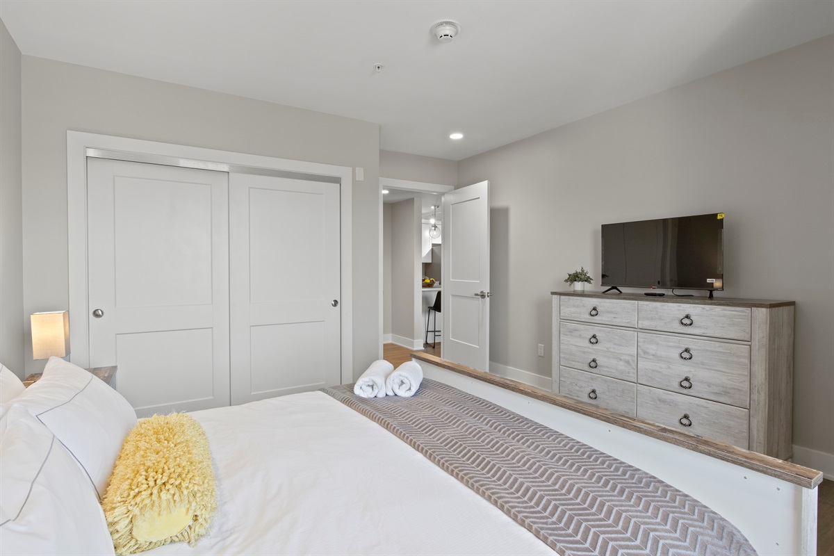 Relax in this bright and spacious bedroom featuring a cozy queen bed, modern lighting, and a serene lake-view window—perfect for your Finger Lakes getaway.
