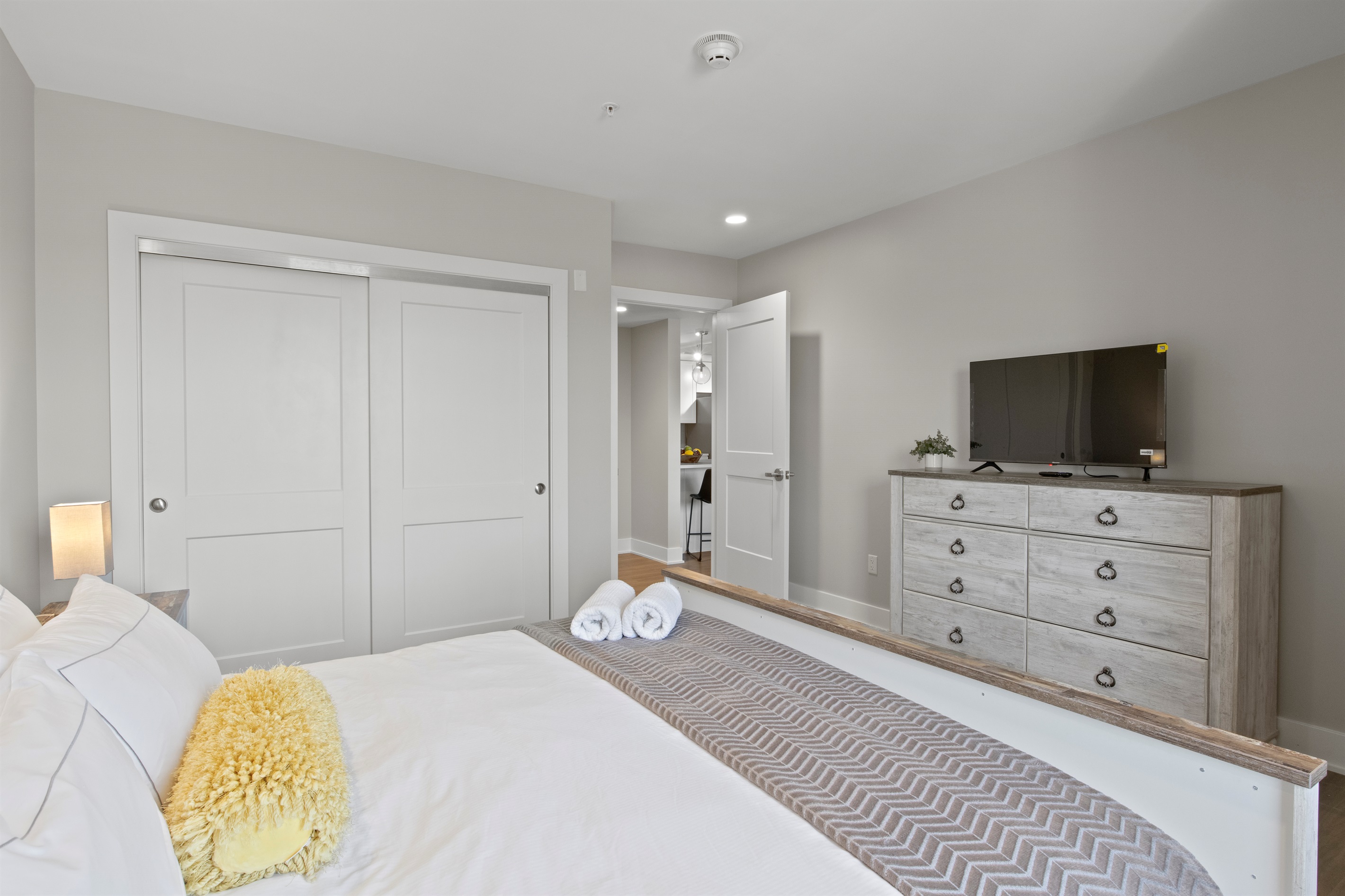 Relax in this bright and spacious bedroom featuring a cozy queen bed, modern lighting, and a serene lake-view window—perfect for your Finger Lakes getaway.