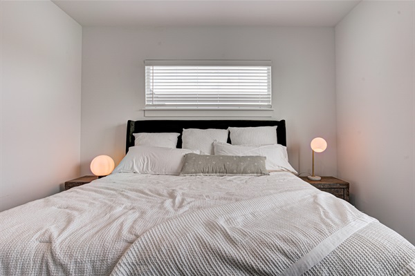 Relax in the serene master bedroom featuring a comfortable king-size bed, soft linens, and cozy pillows. Includes nightstands, lamps, walk-in closet, and full-length mirror for added comfort. 