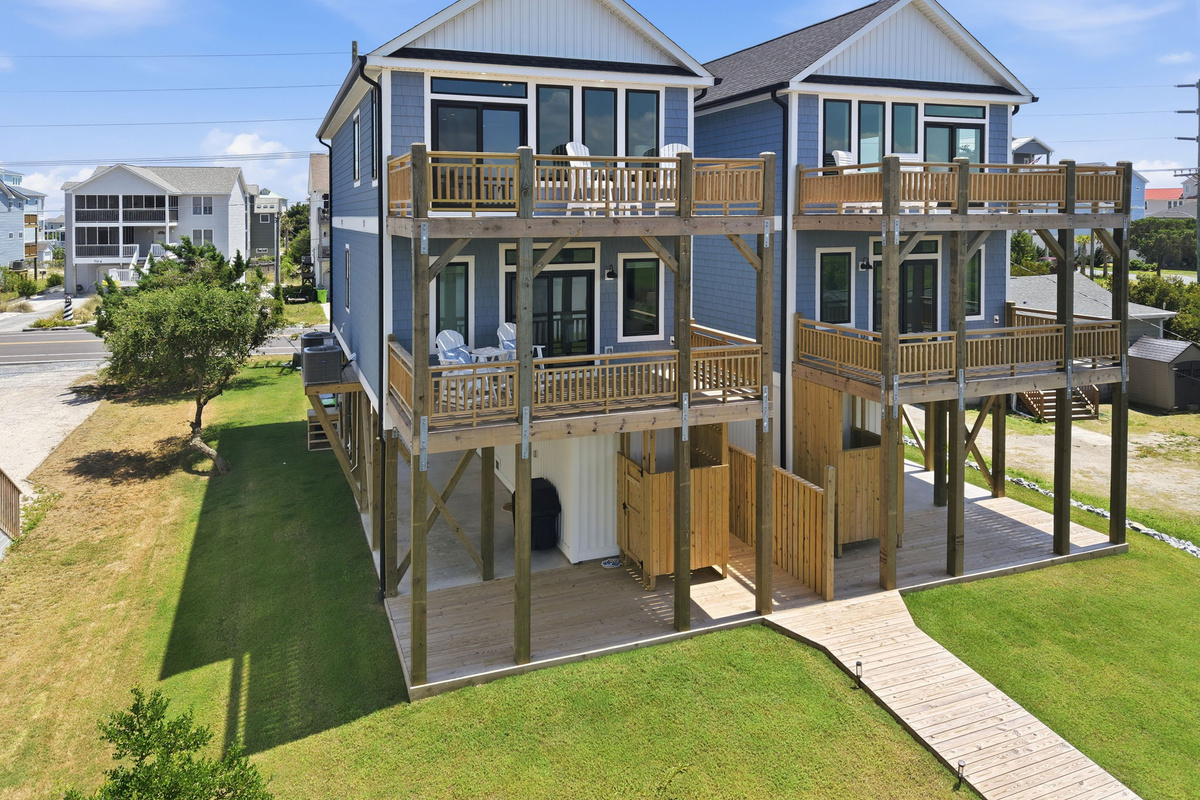 Elevated perspective highlighting multiple outdoor living spaces, covered areas, and the home's beautiful coastal setting