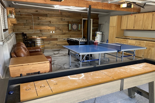 Garage game room includes-shuffle board, table tennis, foosball, darts, and chess table.