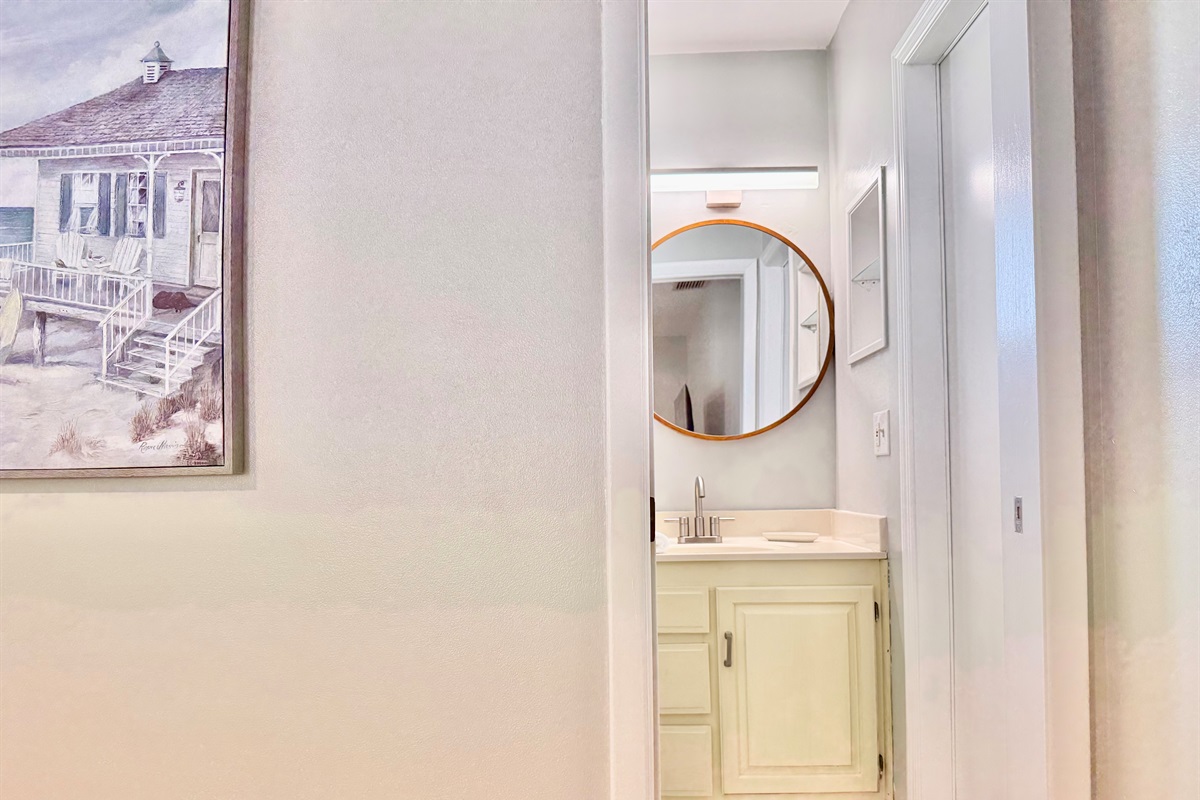 A bright and functional space with vintage charm—complete with a large shower, soft towels, and a stylish round vanity mirror.