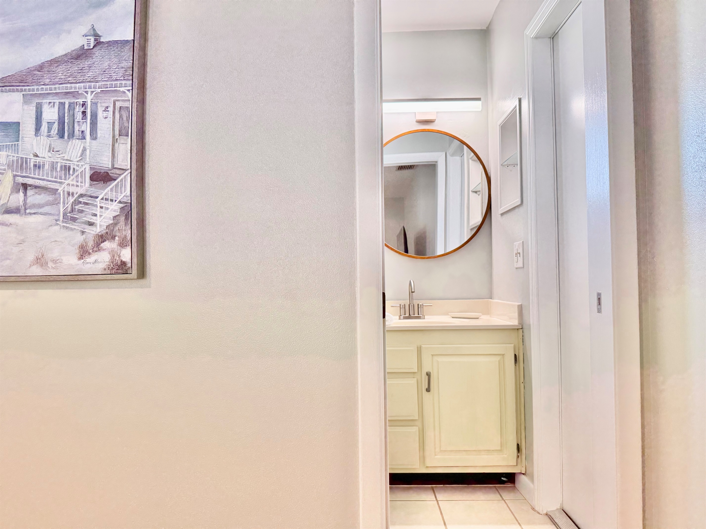 A bright and functional space with vintage charm—complete with a large shower, soft towels, and a stylish round vanity mirror.