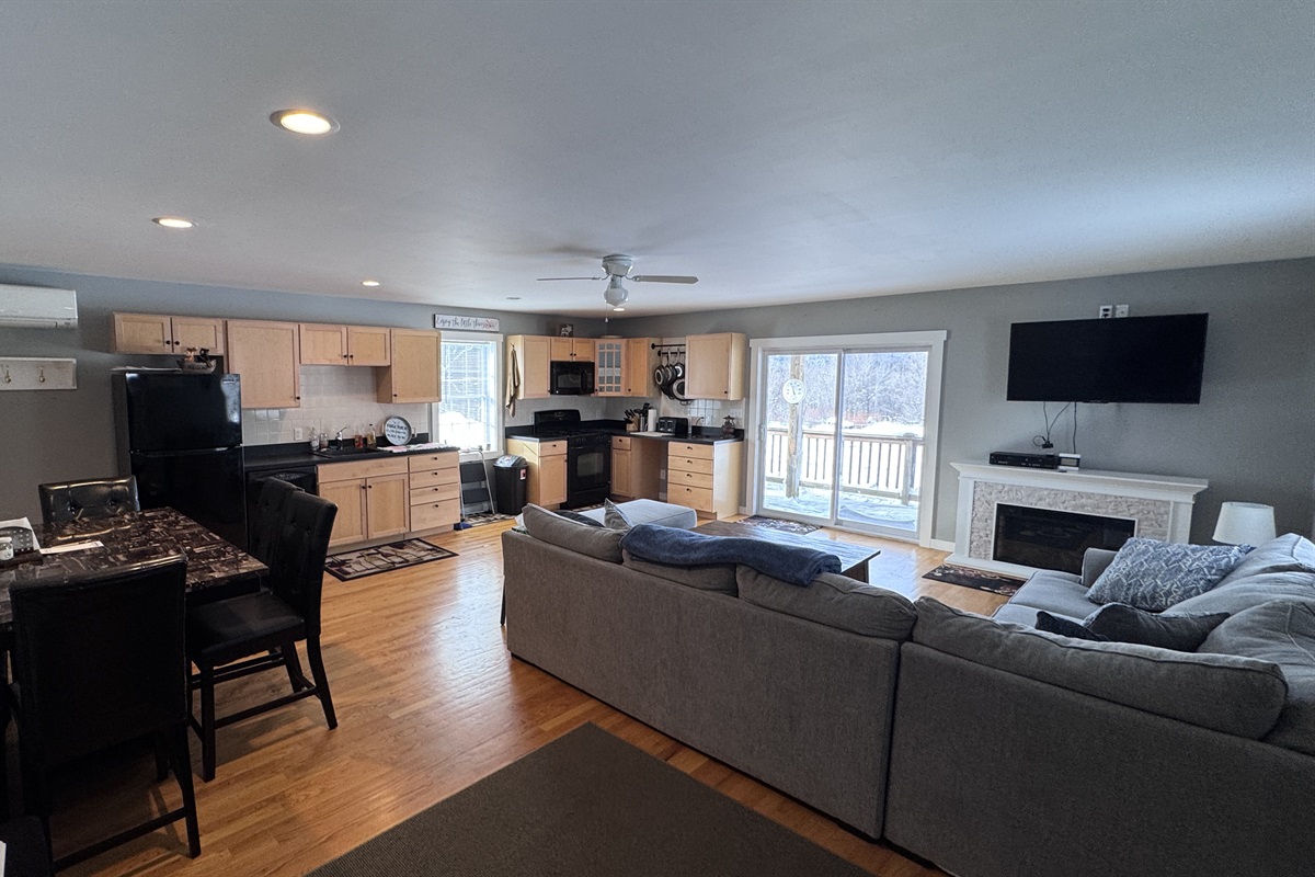 Living room with sizeable L-shaped couch with open concept to kitchen and dining area