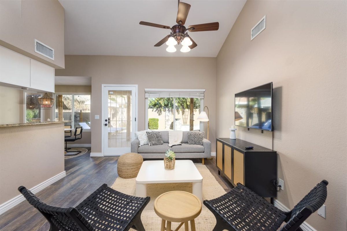 Sitting area with wall-mounted TV, comfortable seating, ceiling fan, and patio door access for relaxed downtime.