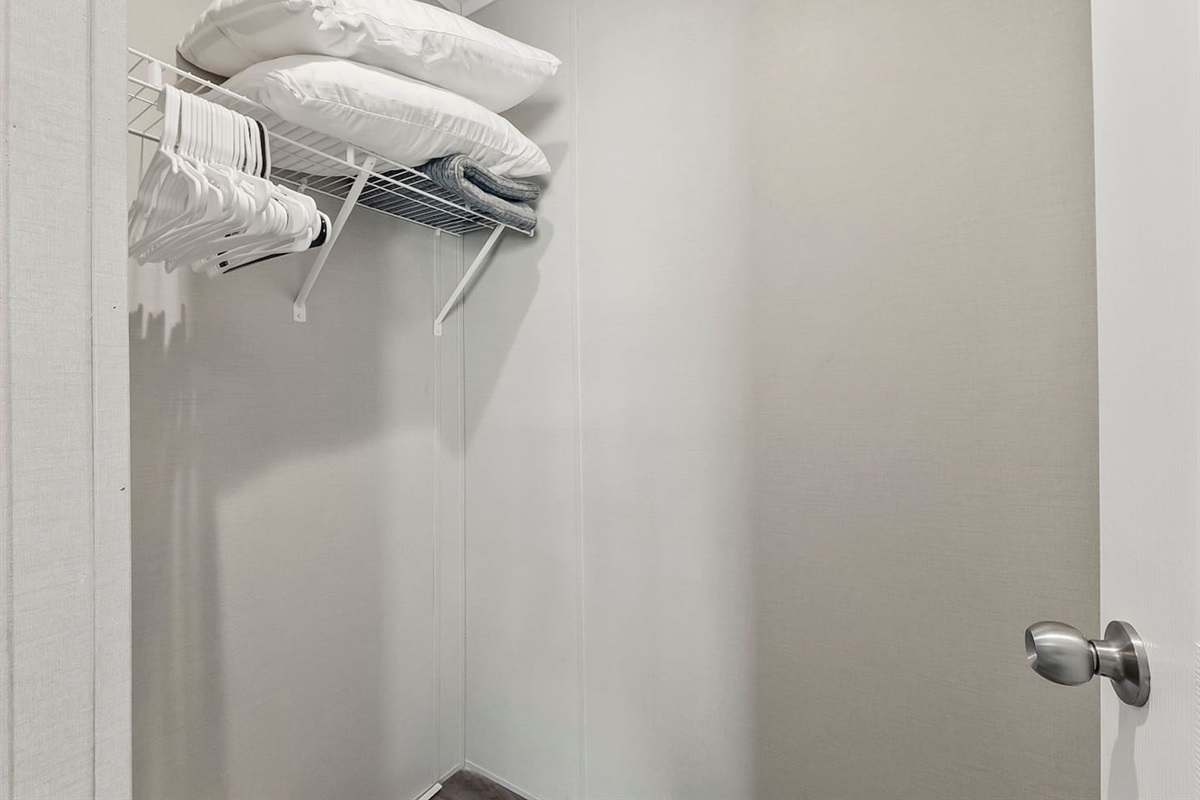 Simple closet space with hangers and extra linens, giving you practical storage during your stay.
