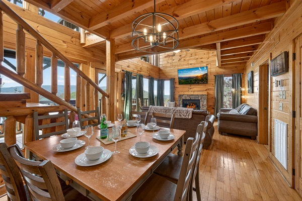 Dining for eight, stone fireplace, and Smoky Mountain views from every window — the main level flows from the kitchen straight through to the living room so nobody's stuck in the back while dinner's happening.