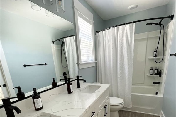 Bright and modern full bathroom with tub/shower combo for guest convenience.