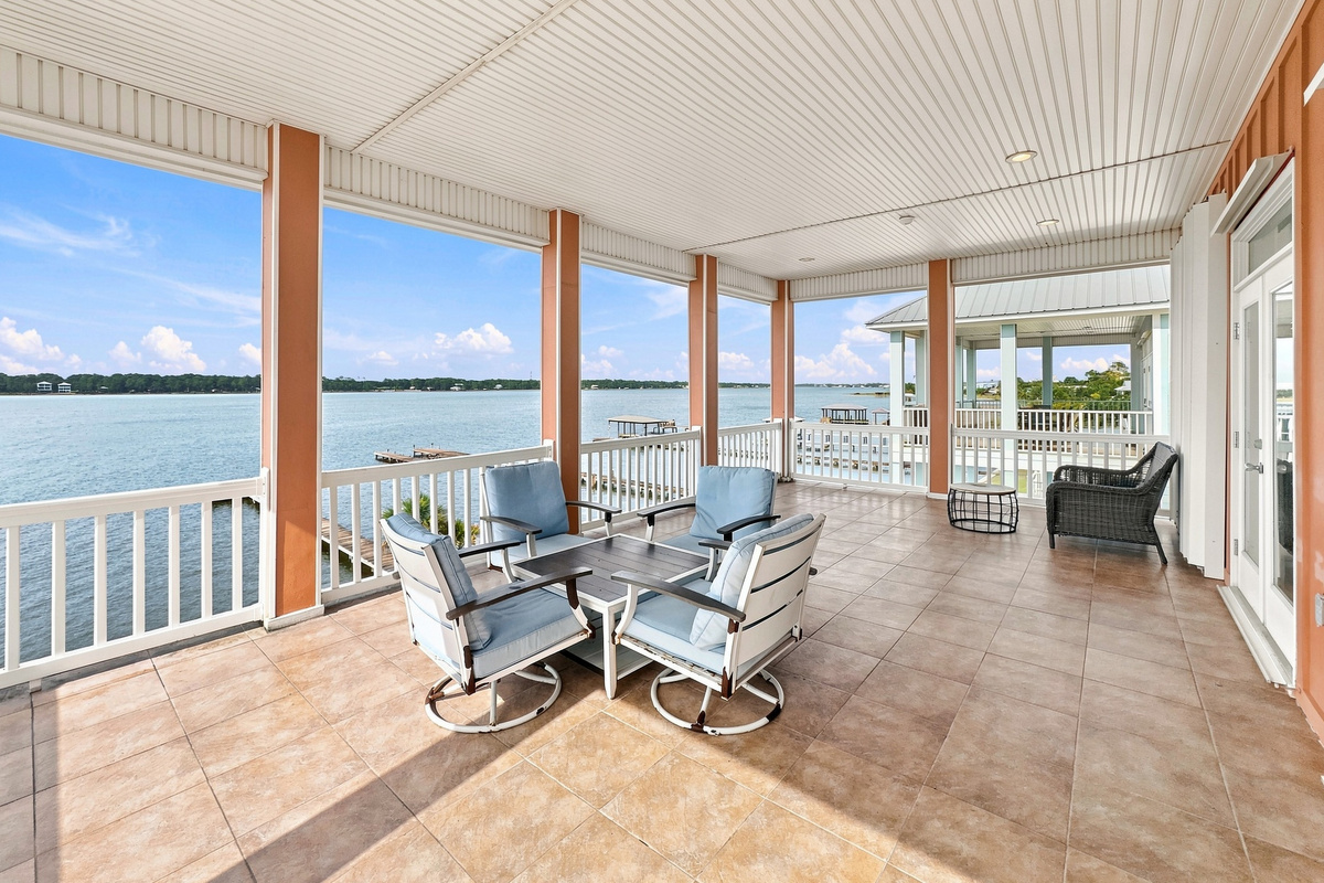 Covered waterfront porch with lounge seating overlooking Little Lagoon