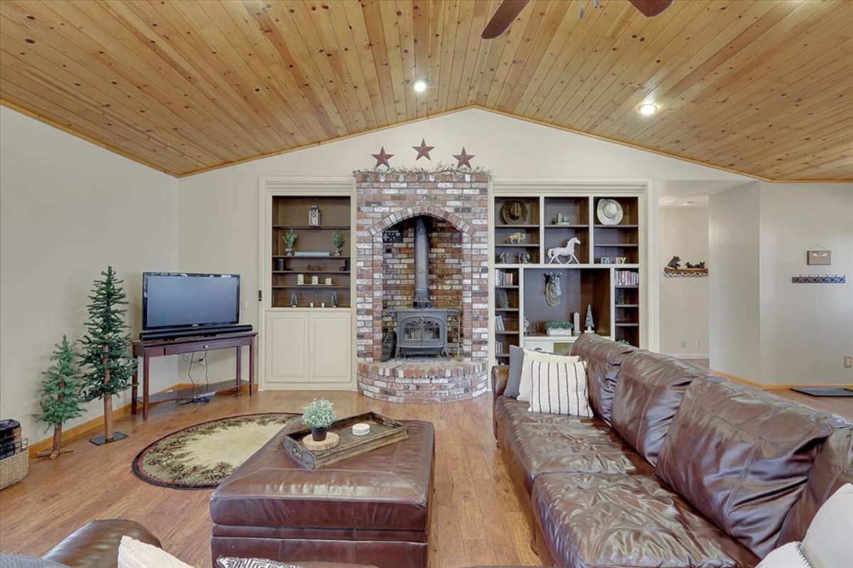 Living room with a brick fireplace, built-in shelves, leather seating, and a classic cabin feel.
