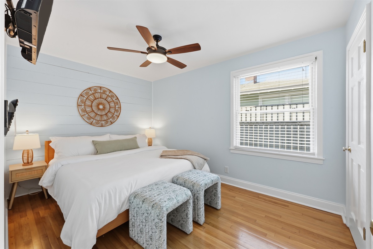 Guest bedroom with calm coastal tones, plush bedding, and sunshine filled windows