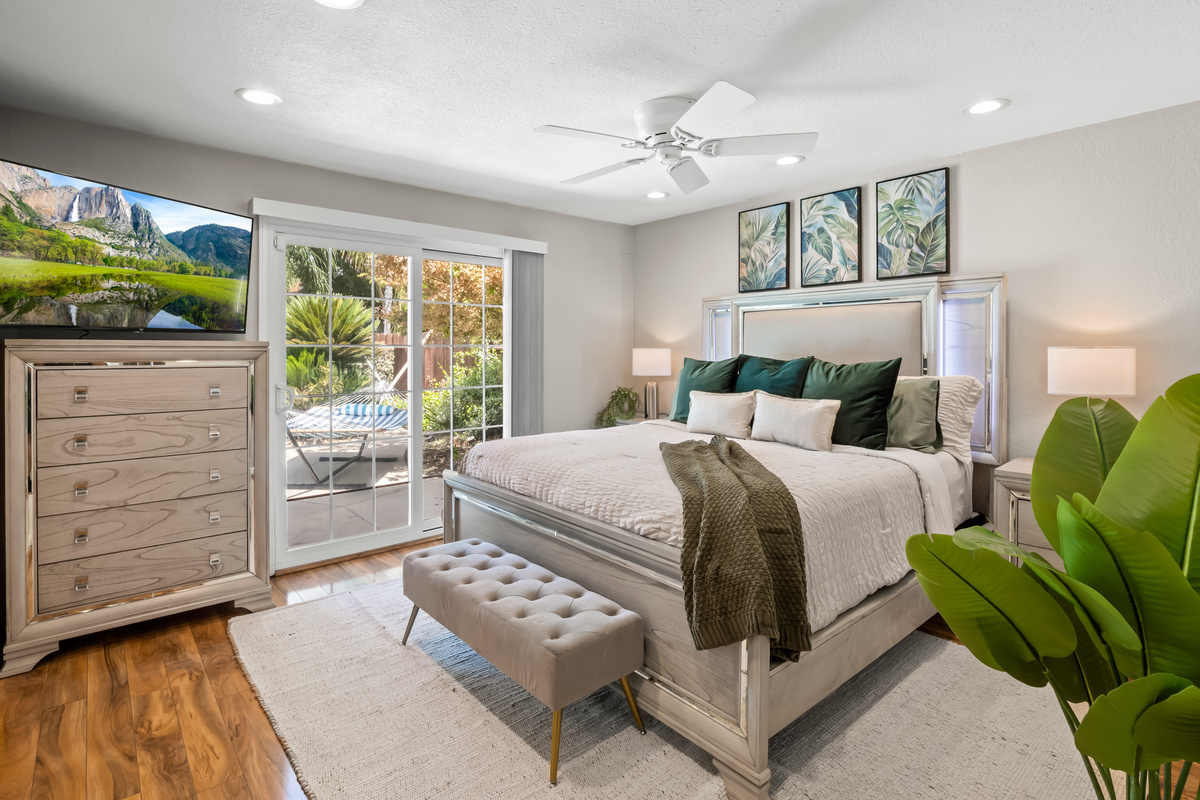 Recharge in a beautifully appointed bedroom featuring a large bed, Smart TV, ample storage, ceiling fan, and private access to the pool area, perfect for a relaxing stay.