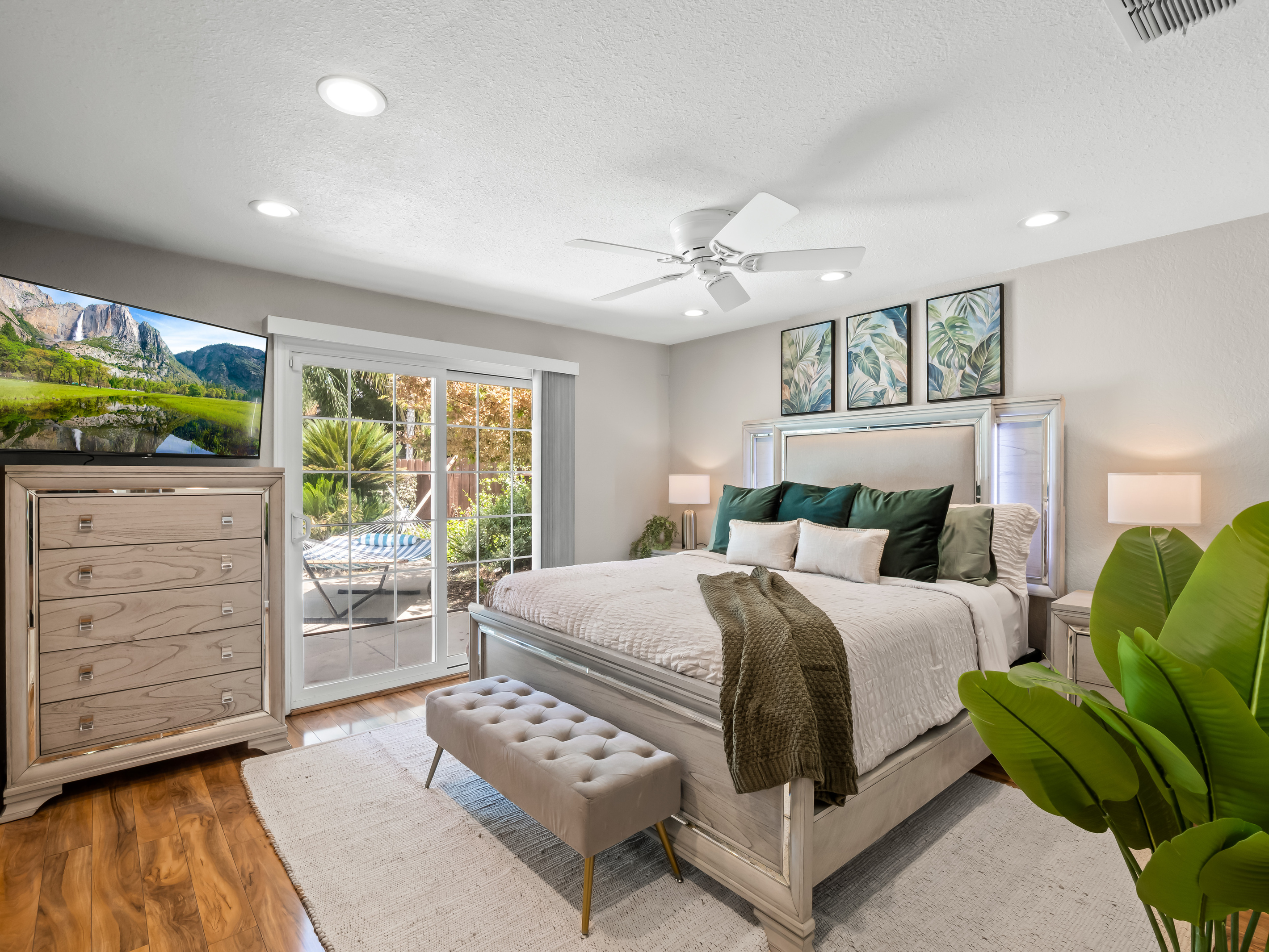 Recharge in a beautifully appointed bedroom featuring a large bed, Smart TV, ample storage, ceiling fan, and private access to the pool area, perfect for a relaxing stay.