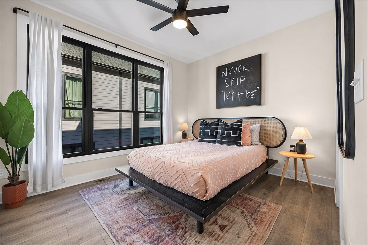 Bright third-floor bedroom featuring a queen bed, private ensuite bathroom, and a smart TV&mdash;designed with fresh linens and modern touches for a comfortable, restful stay.