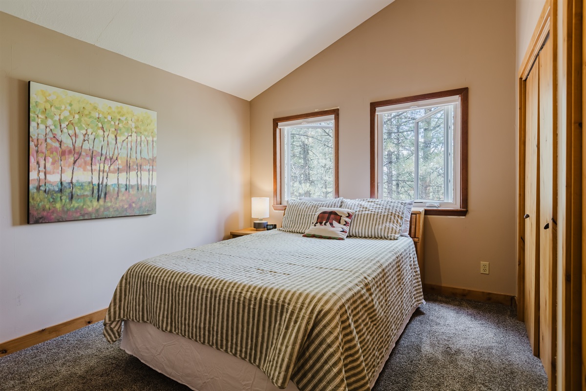 Perched upstairs, this inviting queen bedroom offers peaceful views of the surrounding peaks. The clean, modern design keeps the space light and uncluttered, while cozy textures make it feel like a true mountain hideaway.