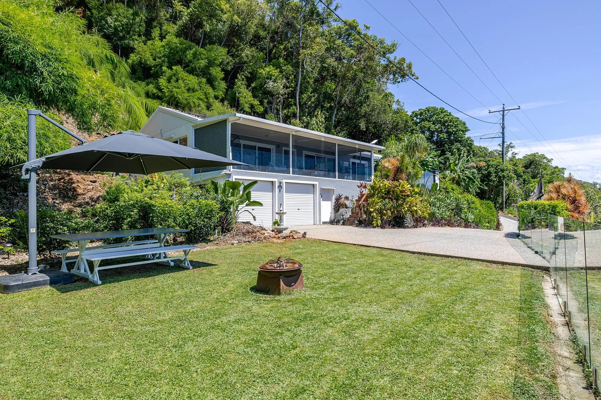 The front lawn, shaded outdoor table and wide driveway give Nicos Butterfly Beach House practical outdoor space before heading inside.