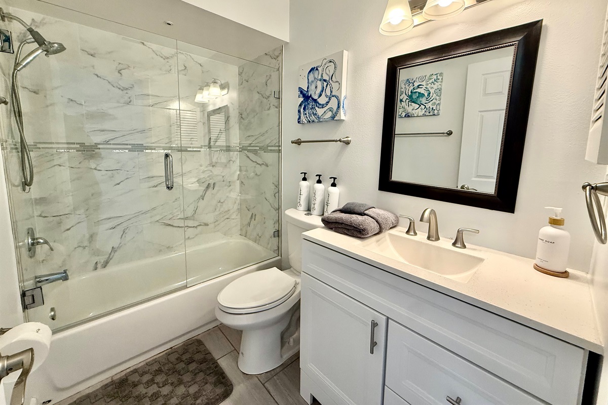 A bright and airy full bath with a sparkling glass shower/tub combo and contemporary vanity.