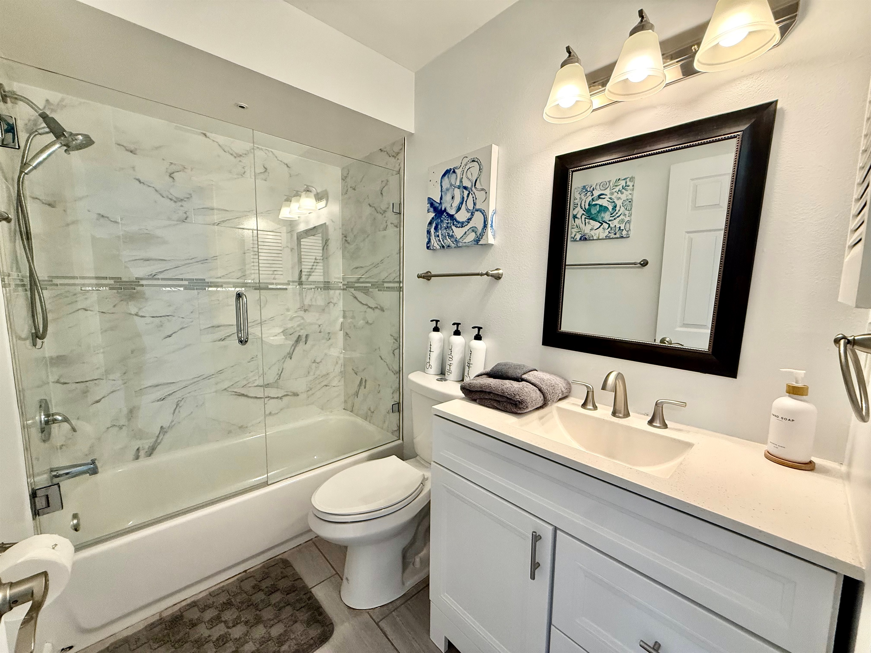 A bright and airy full bath with a sparkling glass shower/tub combo and contemporary vanity.