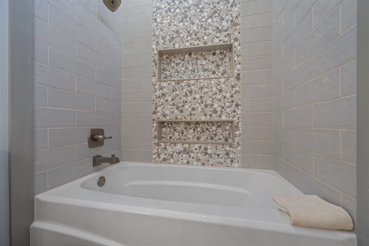 Soaking tub/shower combination with sleek tilework and built-in niches: a spa-like touch to the master bathroom