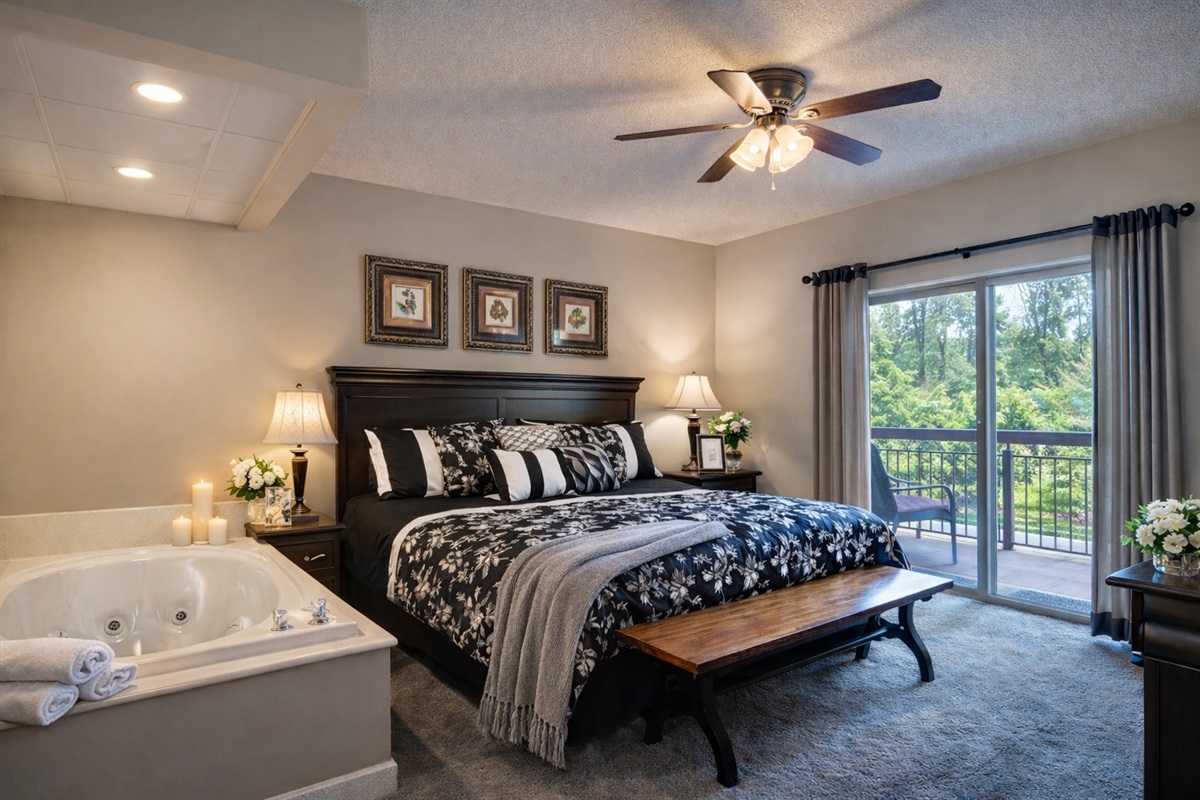 Spacious primary suite featuring king bed, spa-style jacuzzi tub, and balcony access for a relaxing mountain retreat.