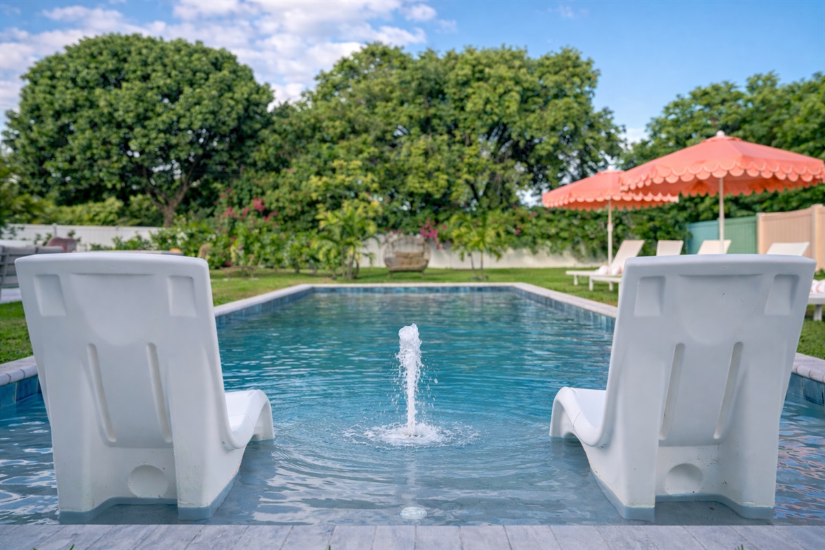 In-pool loungers paired with a small bubbling fountain—cool off, unwind, and soak in the Palm Beach sun as water gently splashes between you, surrounded by lush greenery and total privacy.