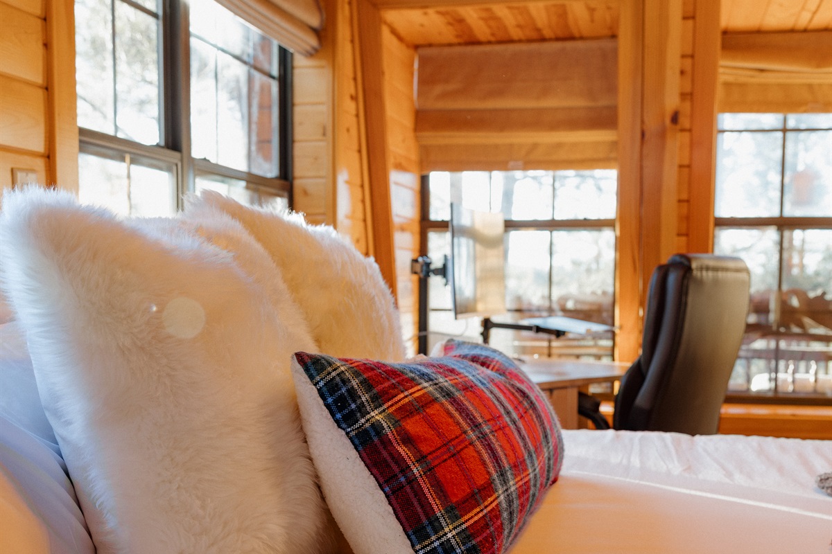Plush bedding with faux fur and tartan accents creates a cozy retreat at Poppywood Pines. This comfortable Show Low bedroom offers forest views and restful nights, perfect after exploring White Mountains hiking trails, fishing lakes, and outdoor adventures