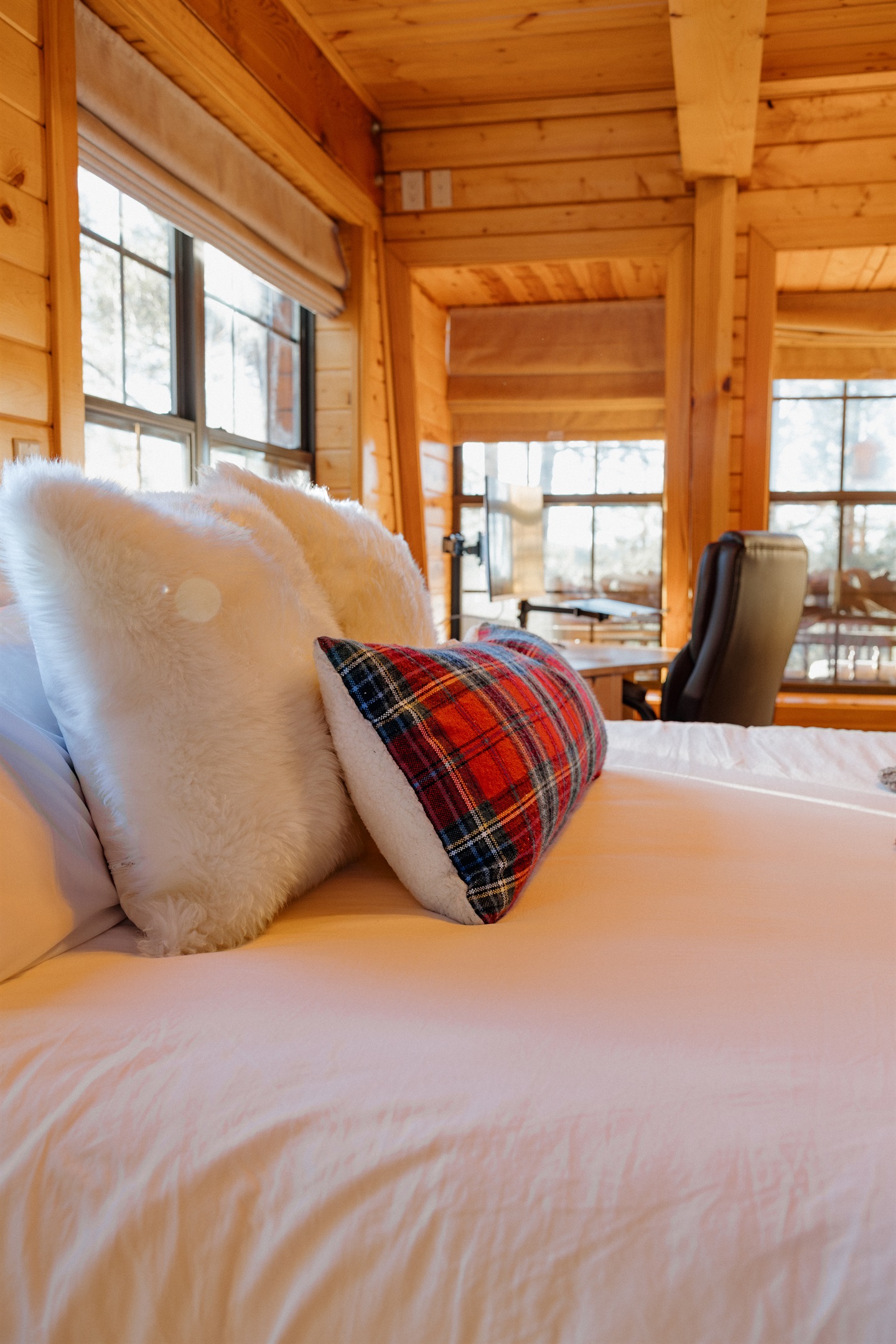 Plush bedding with faux fur and tartan accents creates a cozy retreat at Poppywood Pines. This comfortable Show Low bedroom offers forest views and restful nights, perfect after exploring White Mountains hiking trails, fishing lakes, and outdoor adventures