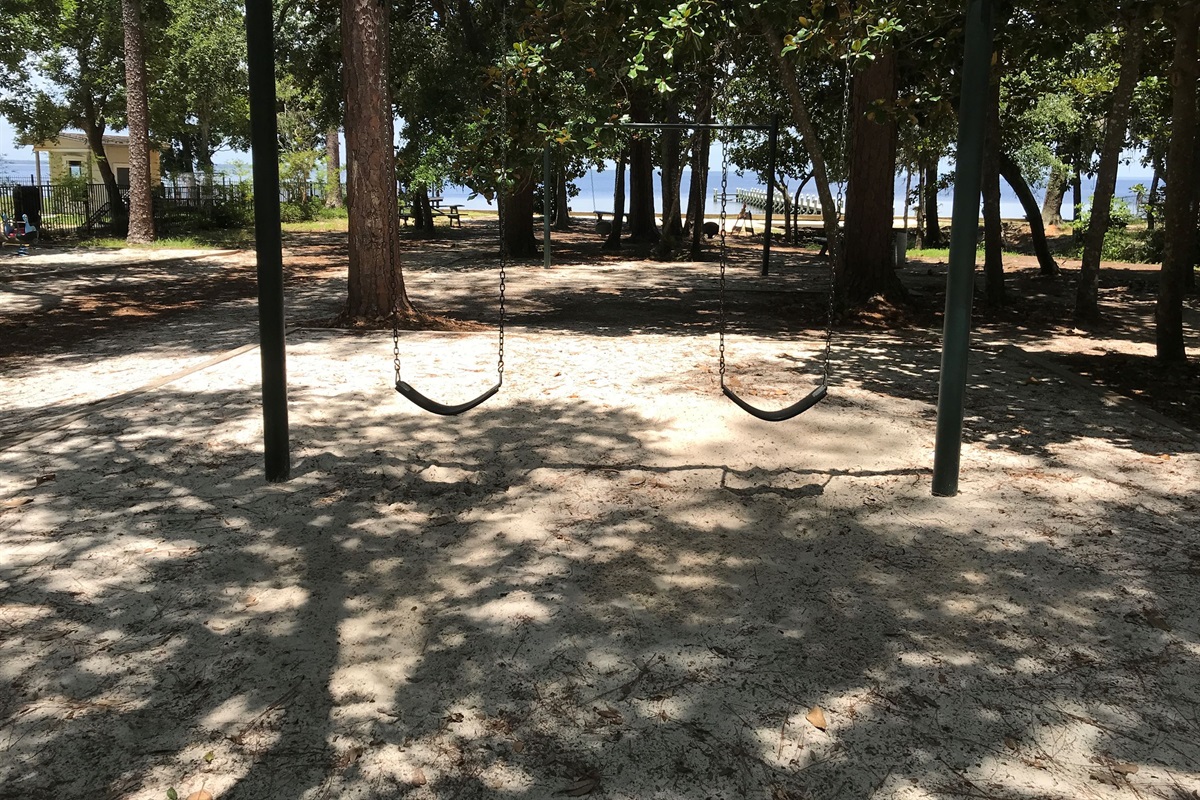 Enjoy a peaceful park setting with classic swings nestled beneath tall trees and natural shade. Just steps from the water, this family-friendly area is perfect for letting kids play while taking in the relaxing outdoor surroundings.