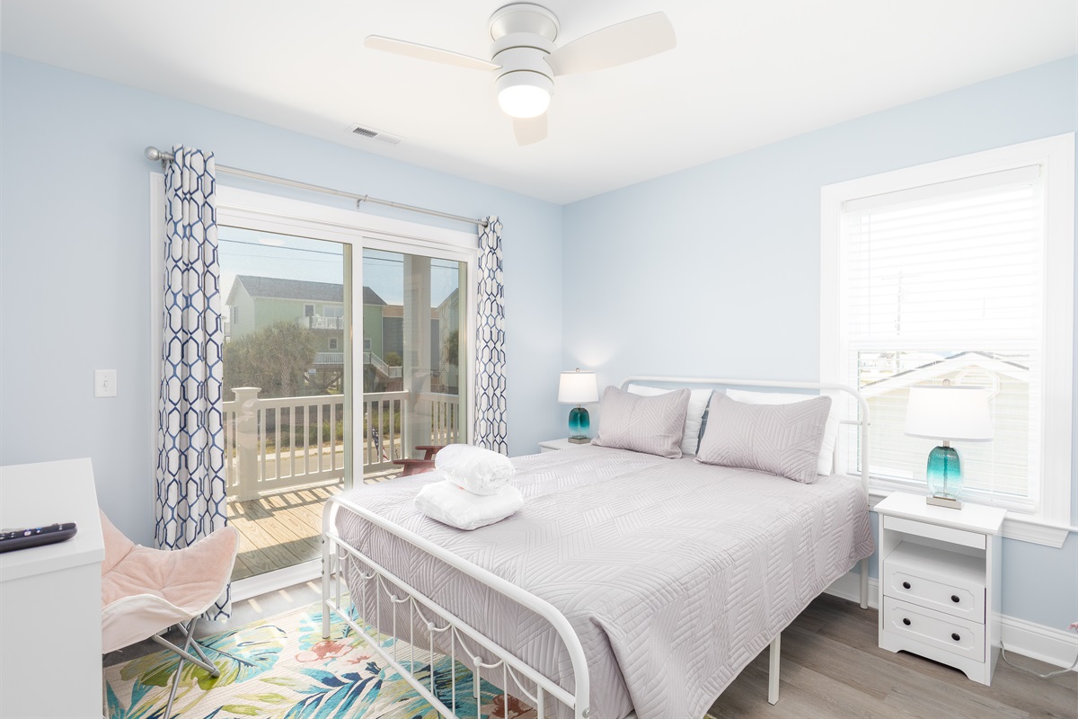 A cozy queen room with direct balcony access, ample closet space, and a smart TV