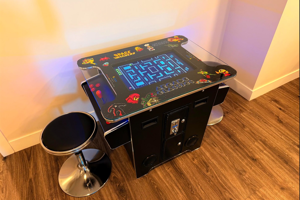 Retro arcade table with built-in games and bar-height stools for easy play.