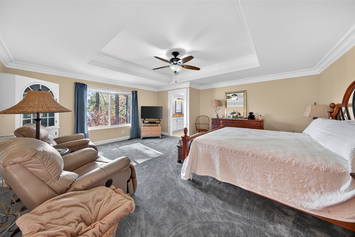 Massive primary suite with a king bed, recliners, and serene lake views.