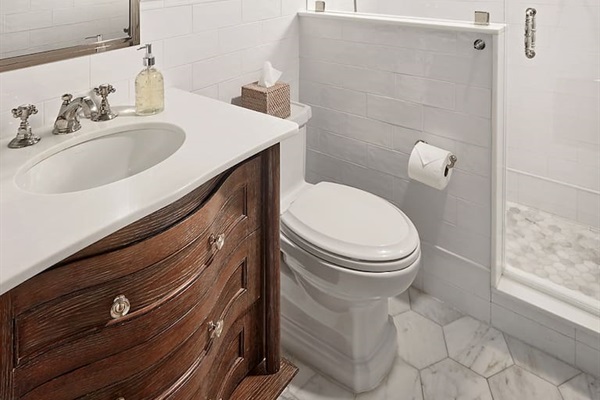 The second bath features a spacious shower with elegant Asian Statuary marble floors, beautiful lighting, and ample storage in the vanity and mirrored medicine cabinet.
