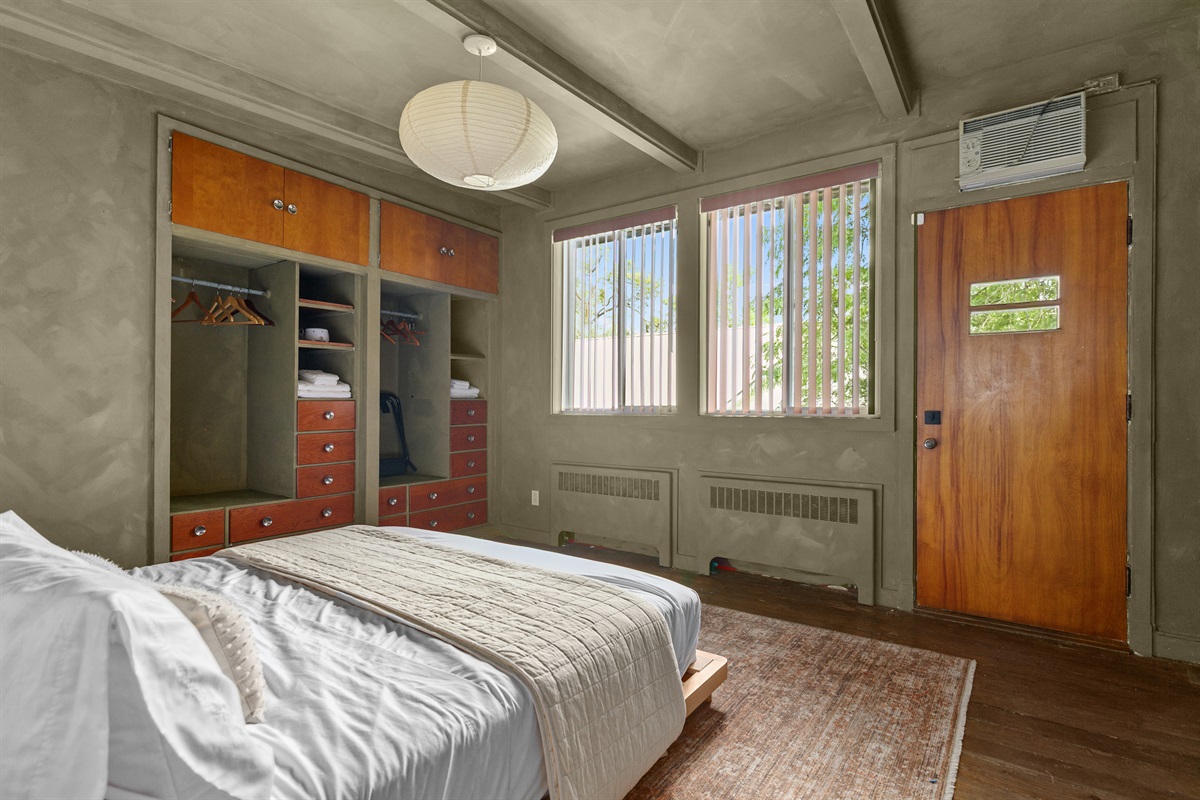 This queen-size bedroom feels bright and welcoming, with sunlight streaming through the windows and plenty of storage to make settling in easy.