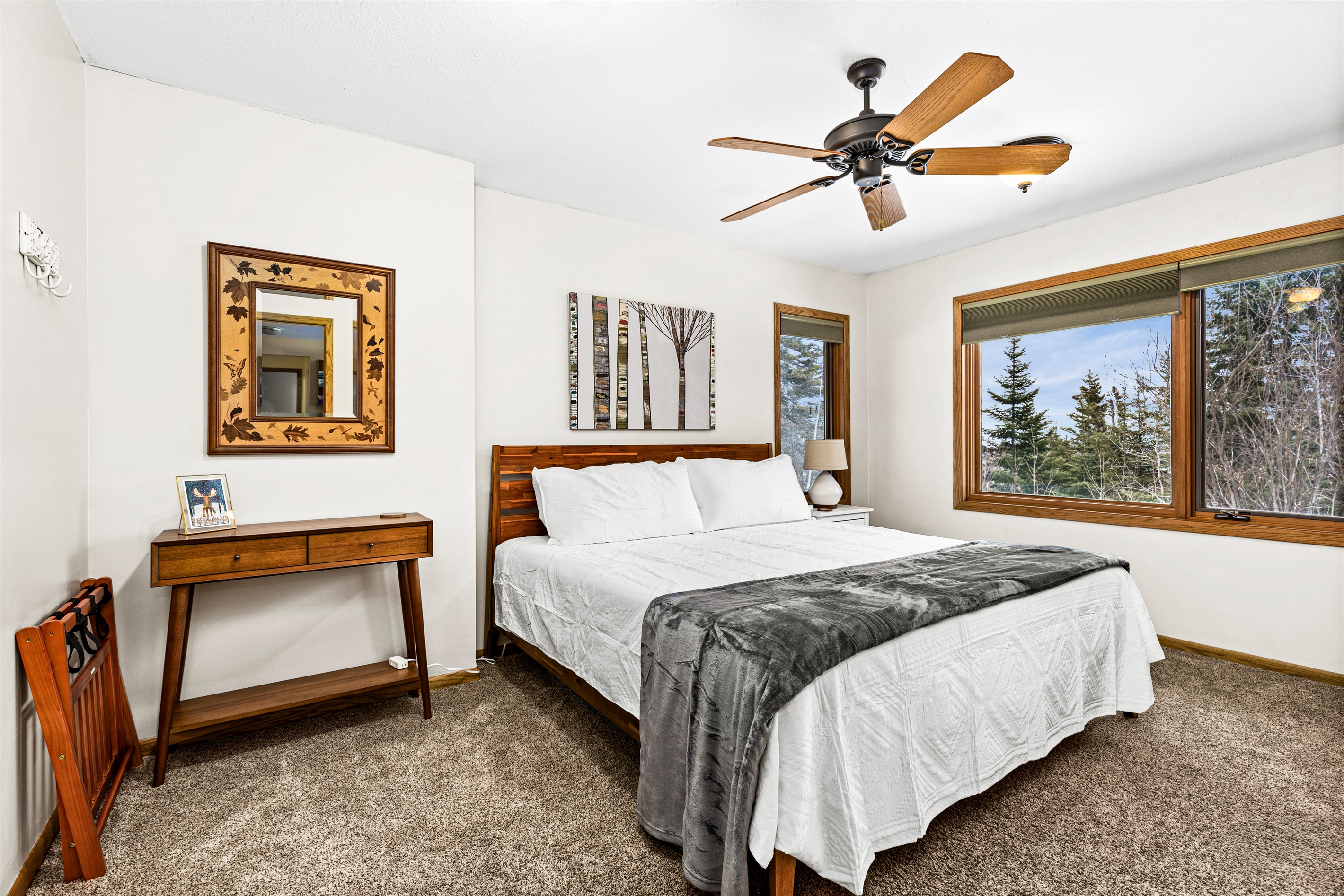 Spacious basement bedroom featuring a comfortable king bed, a ceiling fan for added comfort, and windows that bring in natural light, creating a bright and relaxing retreat.