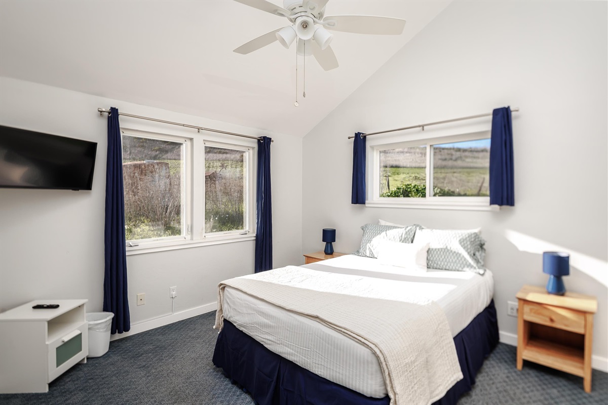 A charming, bright bedroom with views of the ocean and hillside