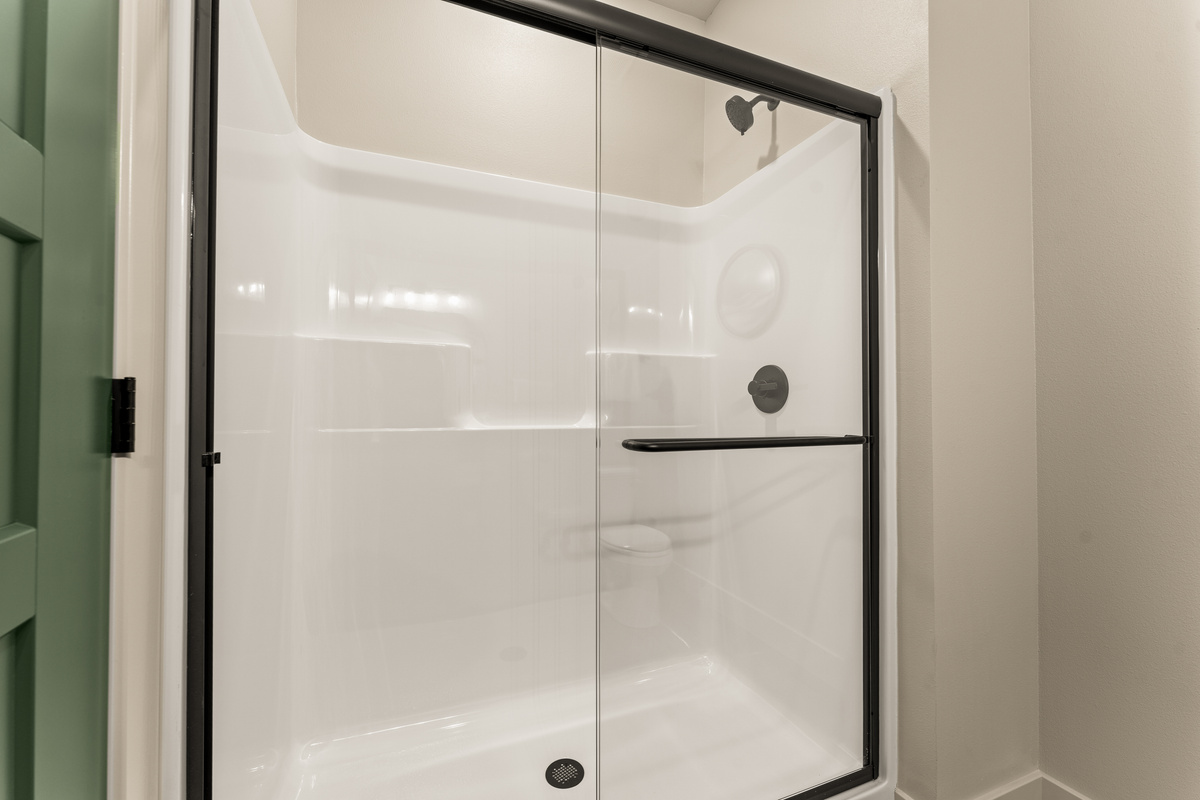 Spacious walk-in shower with sleek black-framed glass doors.