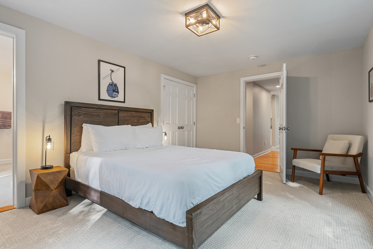 Guest bedroom with queen bed, soft carpeting and a reading chair