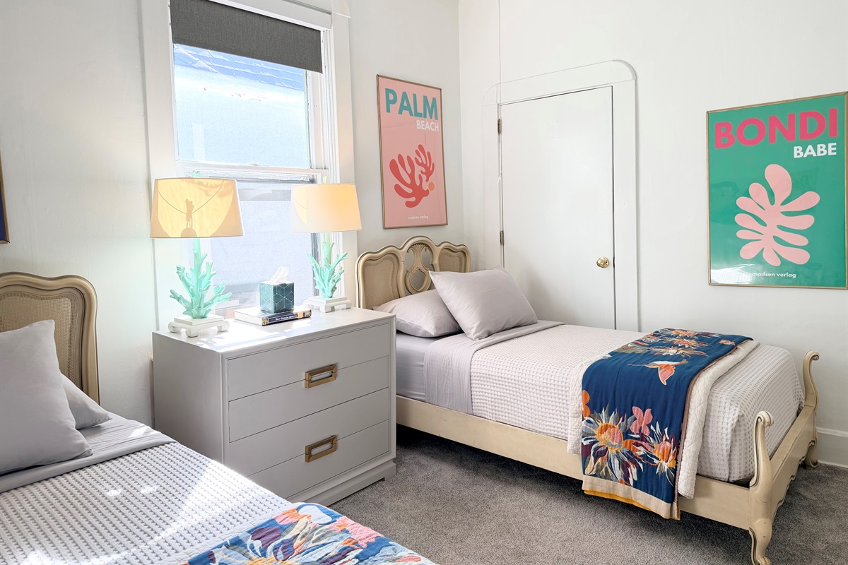 Bright and airy twin bedroom with an easy layout and open garment racks at the foot of each bed — ideal for shared stays, families, or extended visits.