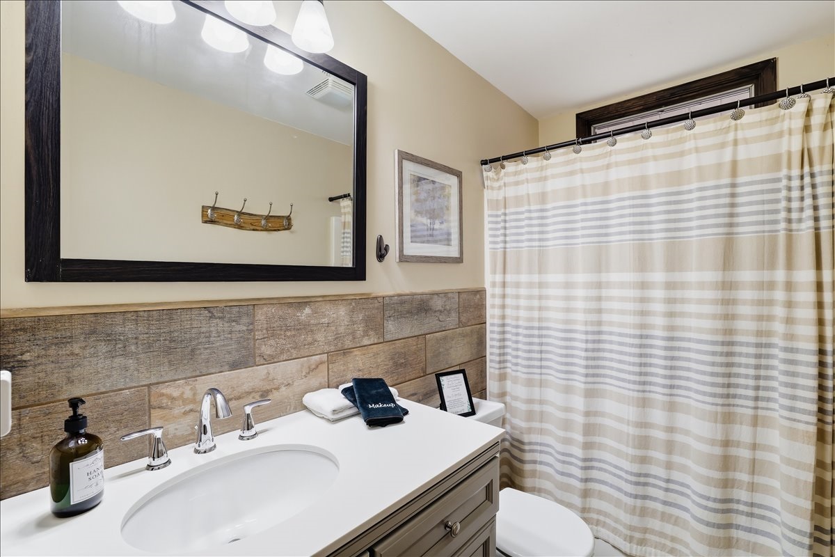 Upstairs full bath features warm wood-look tile, a tub/shower combo, and all the essentials waiting for you