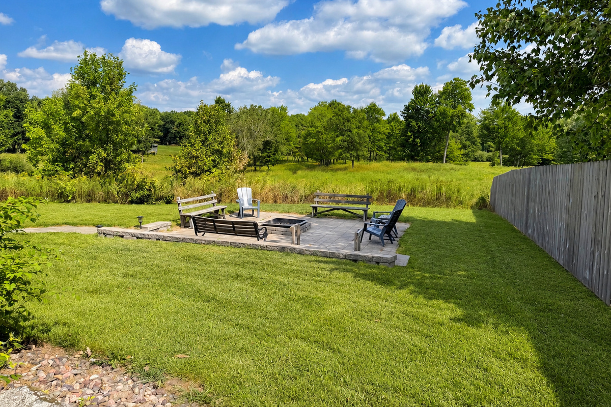 Spacious backyard with patio seating and an outdoor fire pit, perfect for evening bonfires, conversations, and relaxing together beneath the Northwoods sky after a day of outdoor adventure.