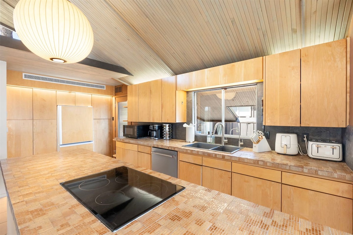 Sleek chef’s kitchen featuring expansive countertops, built-in appliances, and warm wood finishes under a stunning vaulted ceiling.