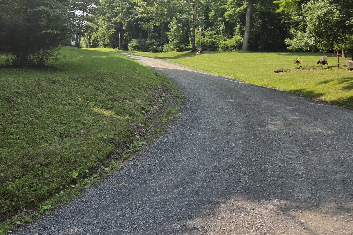 The property is accessed by a winding gravel mountain road with hills and curves.