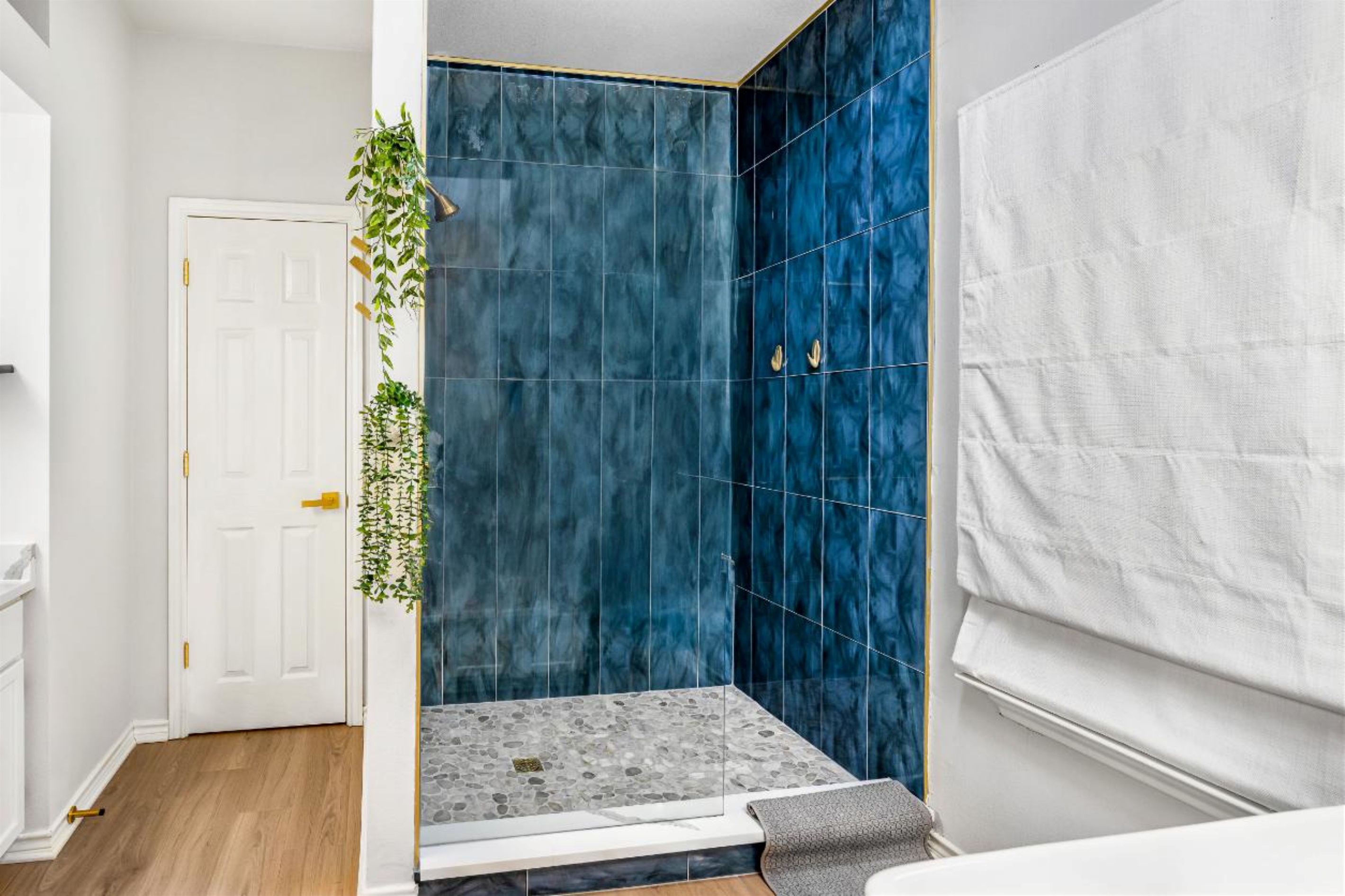 Indulge in luxury in this stunning en suite master bathroom! Enjoy the sleek, glass-enclosed shower with gorgeous blue tiles and gold accents, plus complimentary shampoo, conditioner, and shower gel. Your private oasis awaits—pamper yourself!