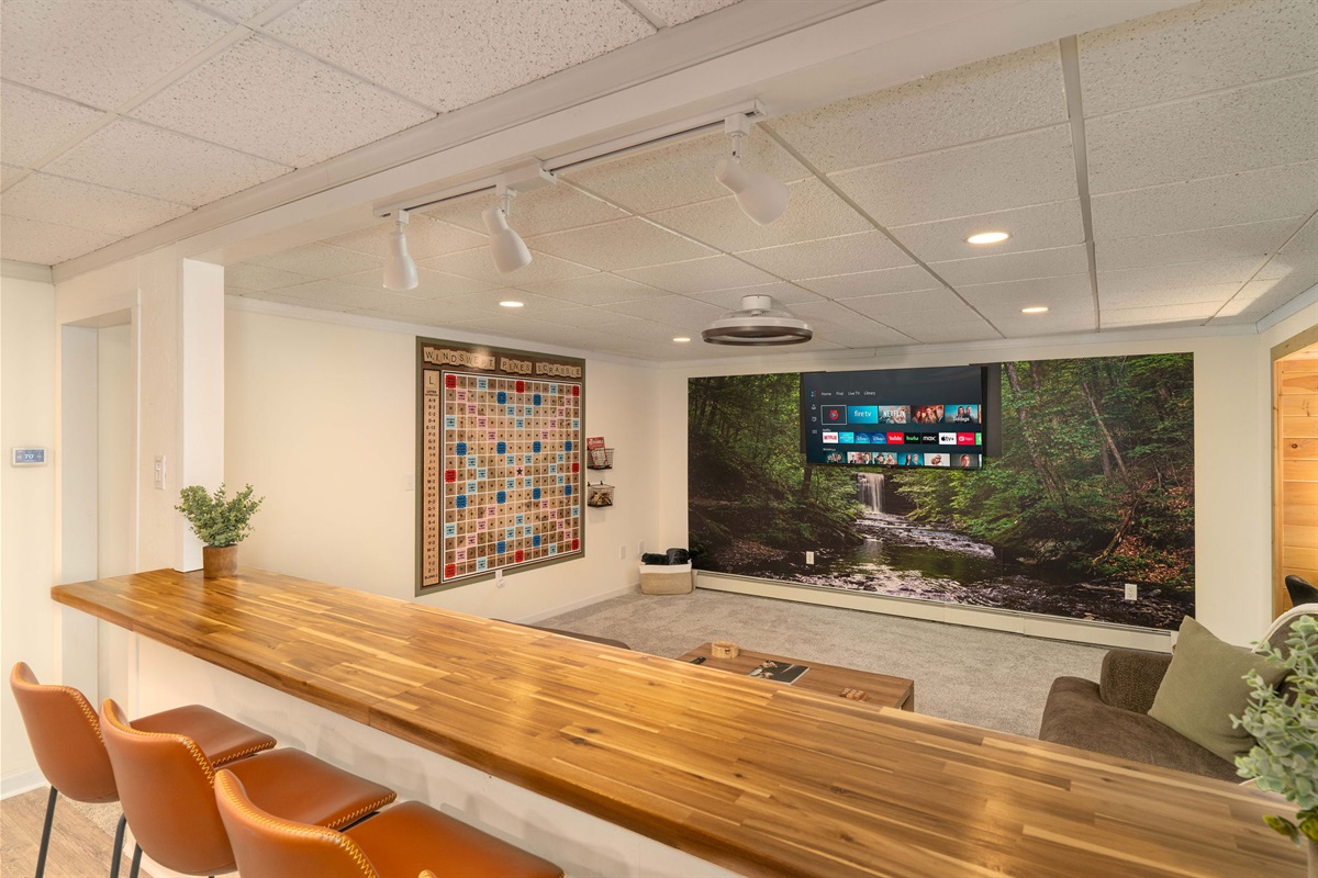 Bar Seating Overlooking the Theater Lounge Cozy lower-level hangout with a huge Smart TV and life-size wall Scrabble nearby.