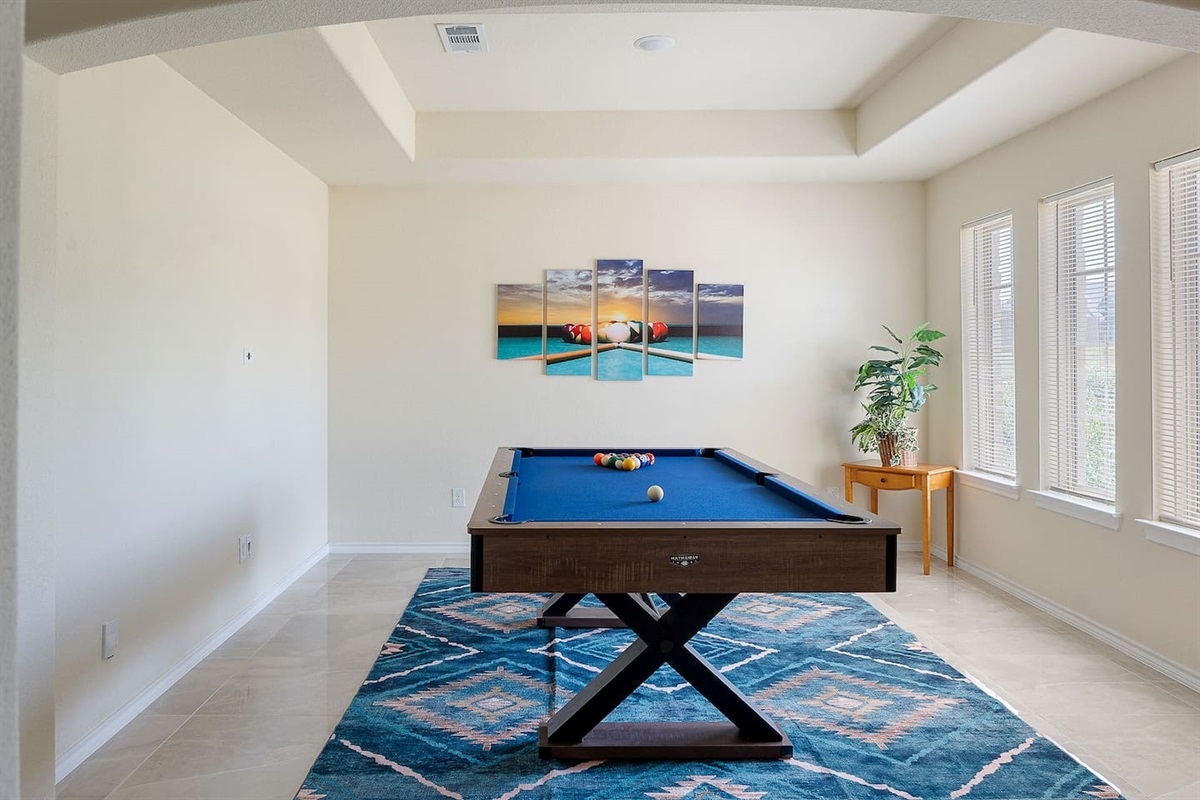 Enjoy a spacious game room with a pool table and large windows letting in natural light.