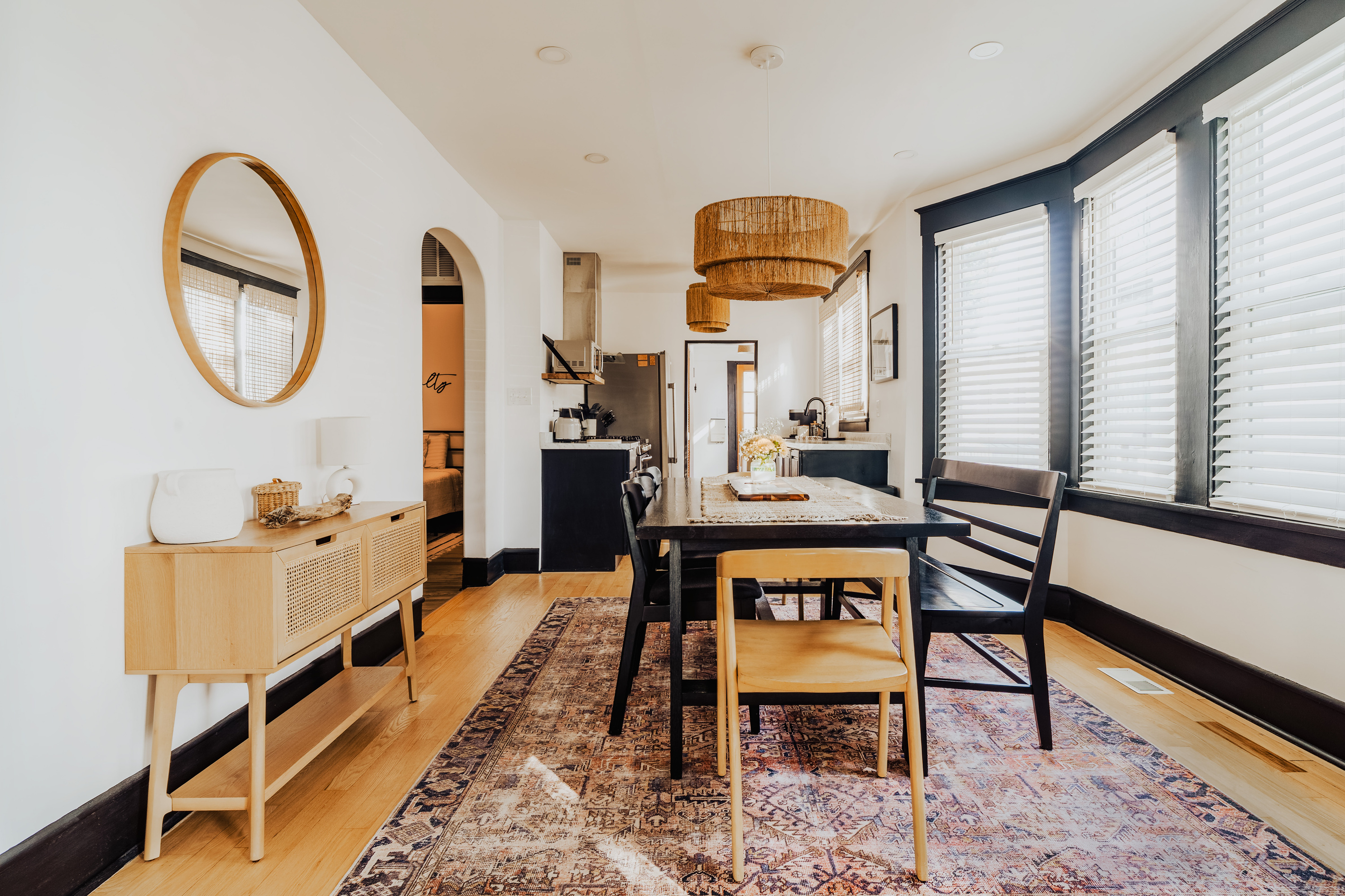 Dining Table Setup with Black Chairs, Light Wood Accent Chair, and Woven Pendant Light