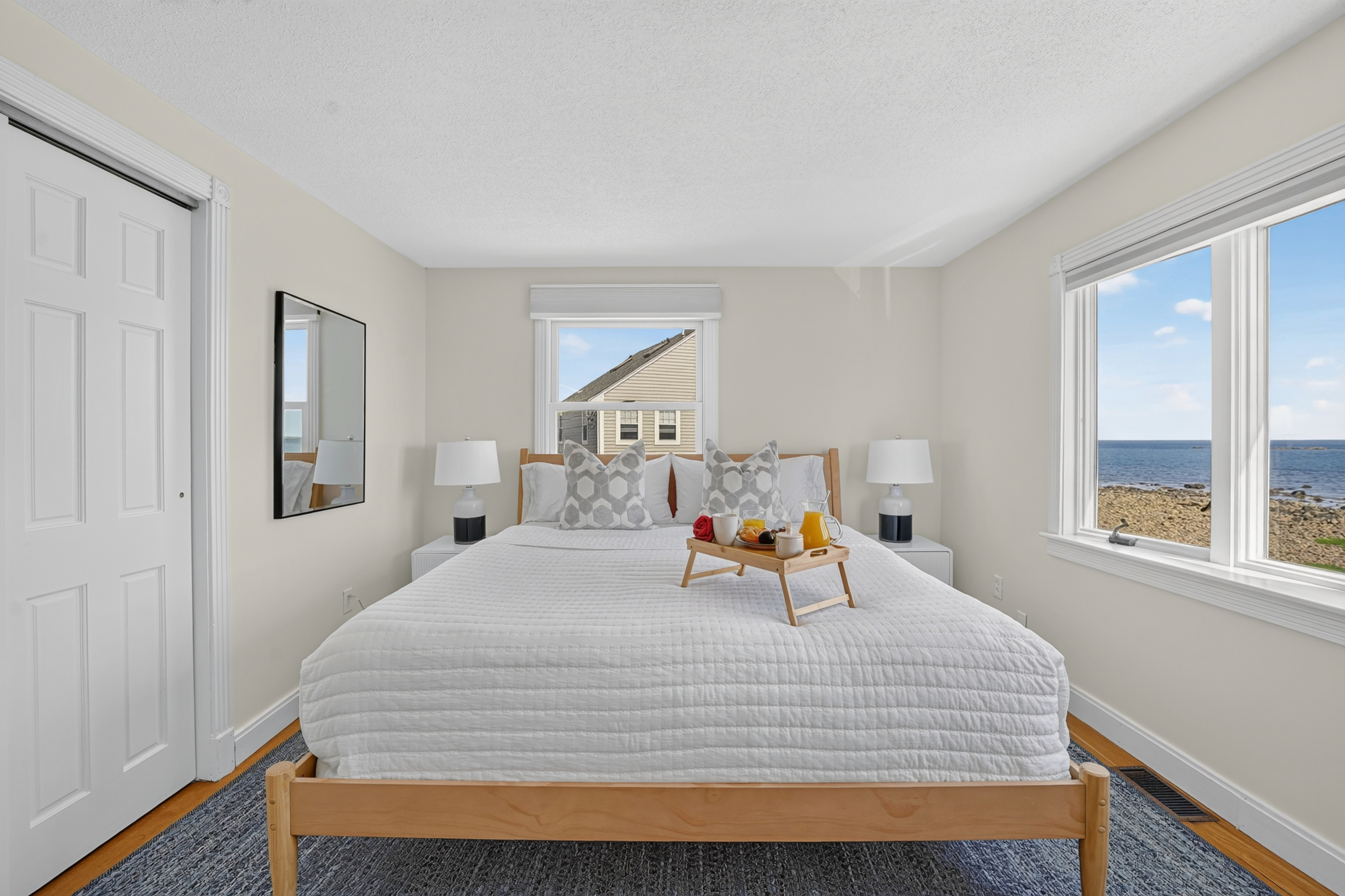 Peaceful bedroom with natural light, comfortable bedding, and windows overlooking the surrounding coastal scenery.